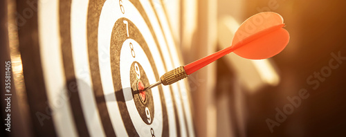 Bullseye or dart board has dart arrow throw hitting the center of a shooting target for business targeting and winning goals business concepts.