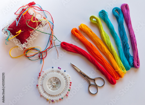 Colored thread, pincushion with needles for embroidery and scissors photo