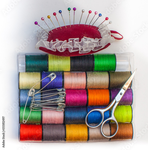 A set of colored threads with scissors, pincushion, pins and needles photo