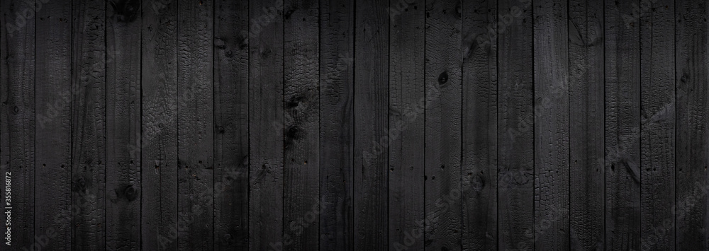 Black wood texture background coming from natural tree. The wooden panel has a beautiful dark pattern that is empty.