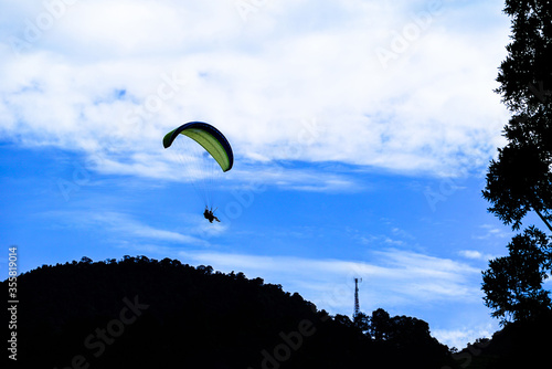 Someone paragliding against the clear day sky. Puncak, Bogor, Indonesia photo