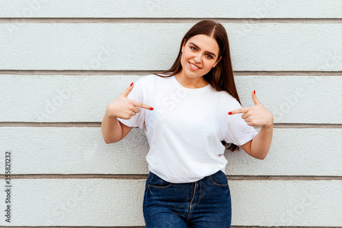 Tablou pe pânză young attractive girl wearing a white t-shirt standing on a grey wall background