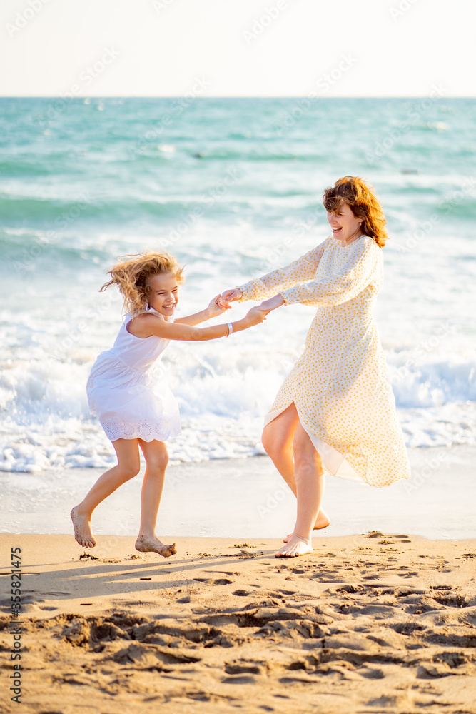 mom and kid walking on sea beach with big waves in windy weather. happy family