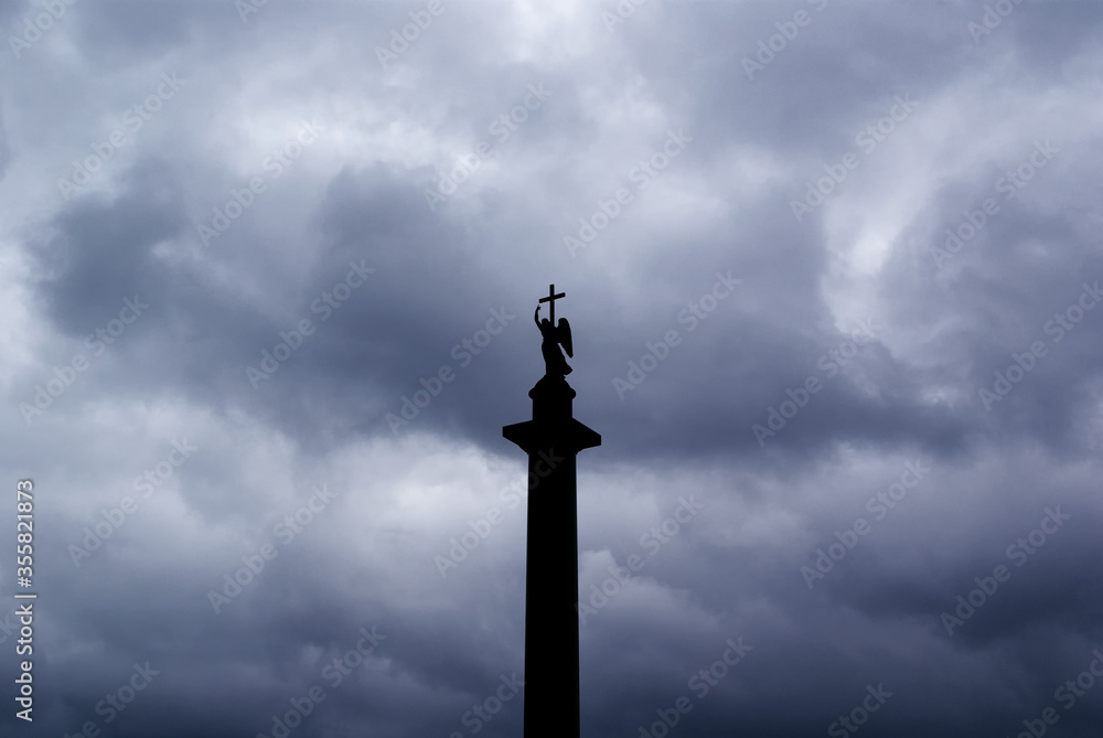 Angel with a cross on the background of storm clouds, the pillar of Alexandria