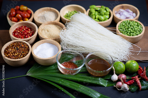 Raw rice flour in a wooden bowl with spices On a dark wood with natural light, focusing on the top of the noodles