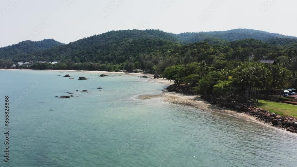 Flight over blue sea and sandy beach with views of the green mountains Flight over blue sea and sandy beach with views of the green mountains