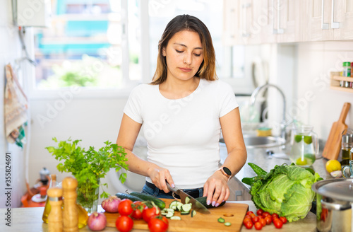 Young colombian housewoman cooking vegetable salad at home