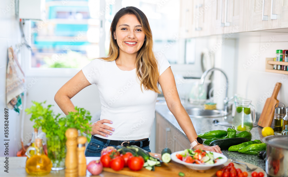 Positive woman with vegetables at kitchen top