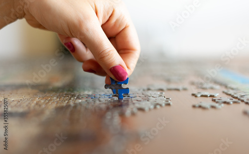 Game - Hand with pink nails while putting the puzzle together.