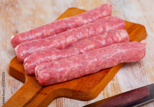 Raw sausages for frying on wooden surface