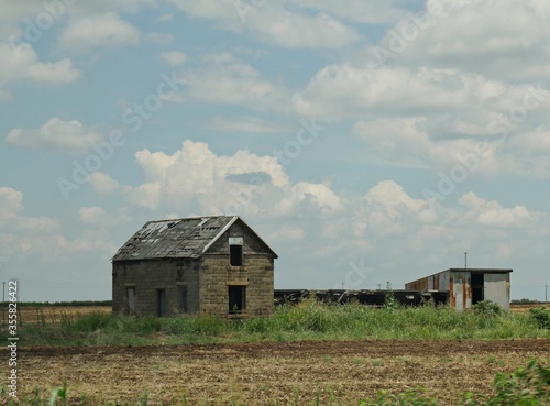 Abandoned broken house with sheds in a farmland