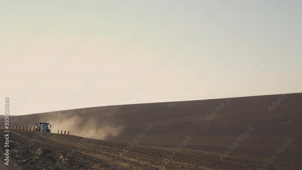 Tractor in the dust working in the field. Tractor cultivating farming land with metal plow . Agricultural work and concept of food industry.4 K Tractor in the dust working in the field. Tractor cultivating farming land with metal plow . Agricultural work and concept of food industry.4 K