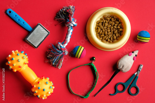 Different pet care accessories and bowl of dry food on red background. Top view, flat lay.