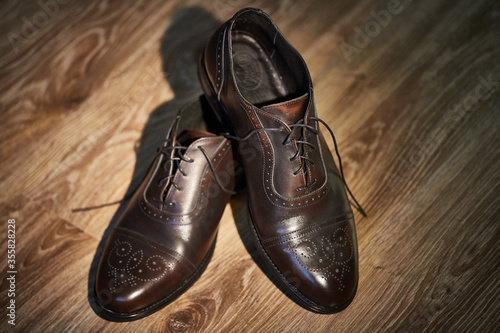 classic brown patent leather shoes with heels on a wooden parquet. groom's morning.