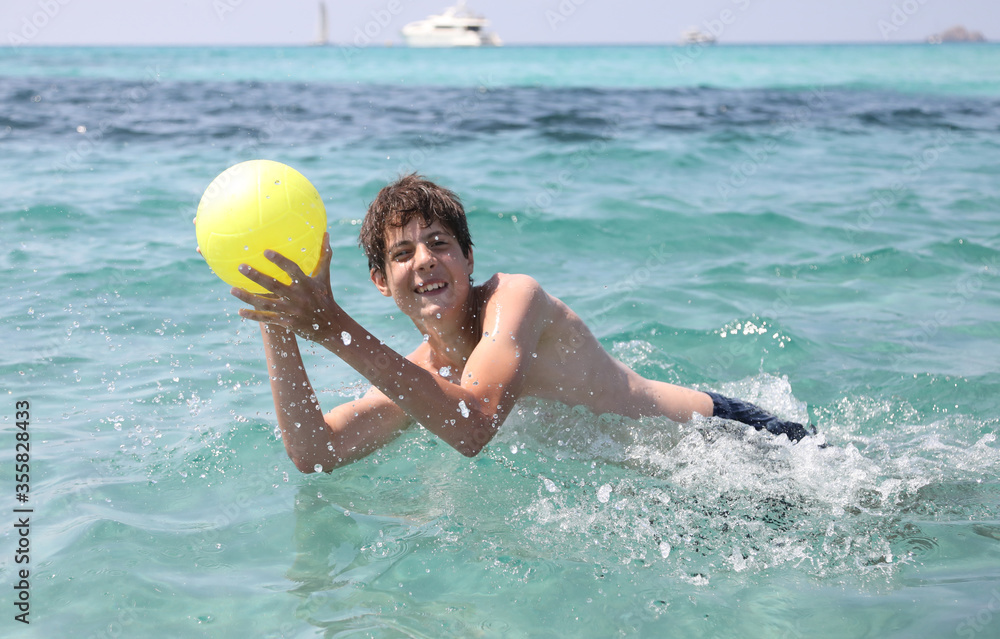 boy plays with a ball on the sea