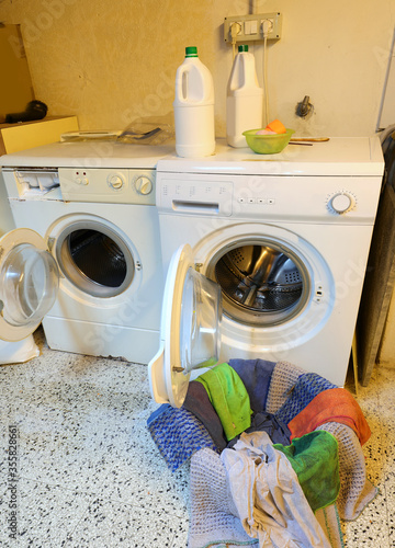 two washing machines and clothes to wash and interior of a laund photo