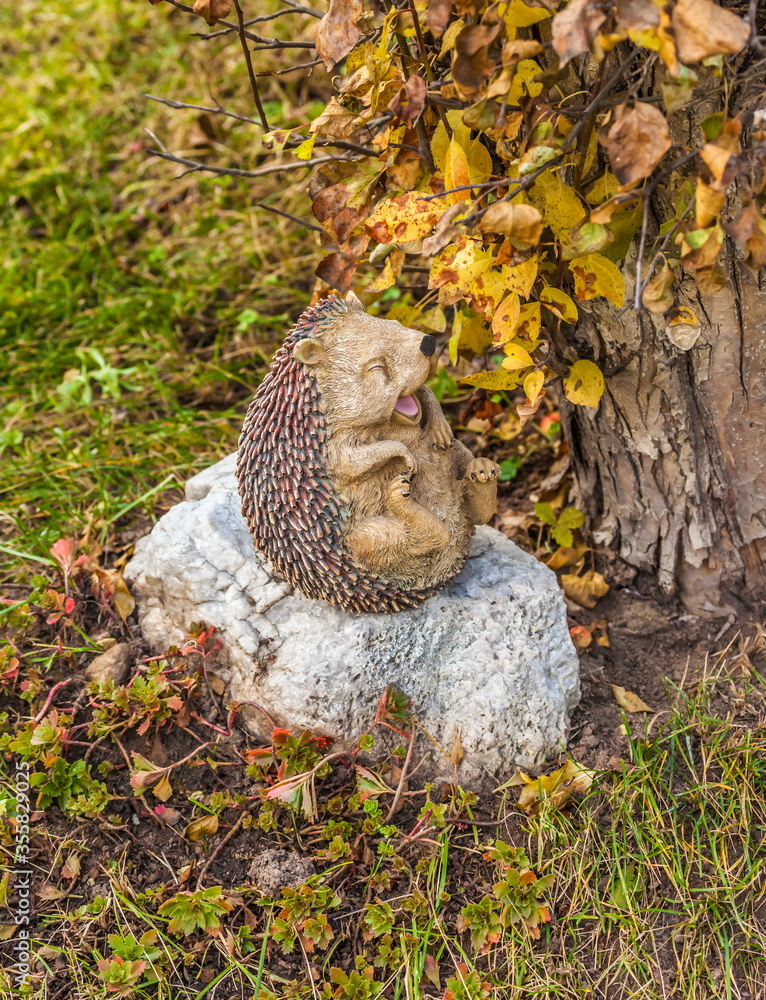 Obraz premium Gypsum statuette of a hedgehog on the background of autumn leaves