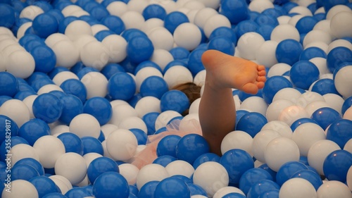 A child’s foot emerges from a pool of blue and white balls at a children’s playground photo