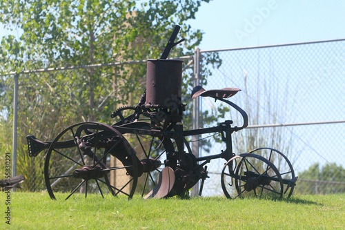 Vintage vehicle with rusty wheels displayed inside a grassy area