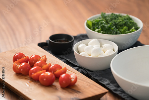 ingredients and empty white bowl on walnut table