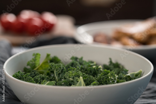 kale salad leaves in white bowl on linen napkin with other ingredients on background