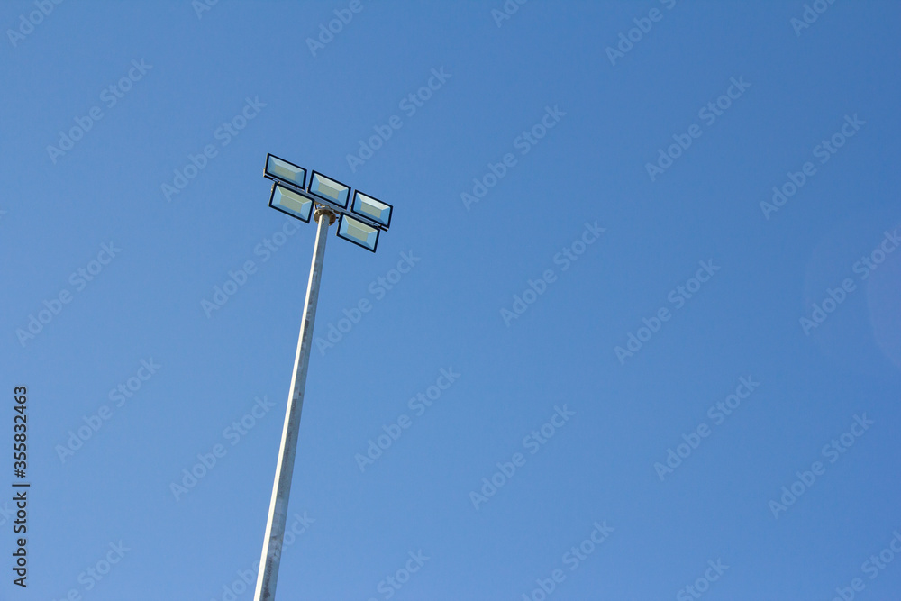 Spotlight in stadium against blue sky. Sports field lighting in the evening Spotlight in stadium against blue sky. Sports field lighting in the evening