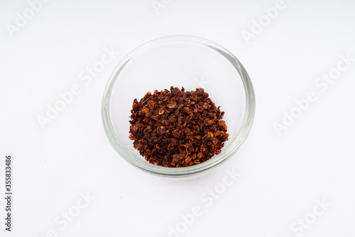 Chilli, red chilli flakes, dried chillies flakes in glass cup on a white background 