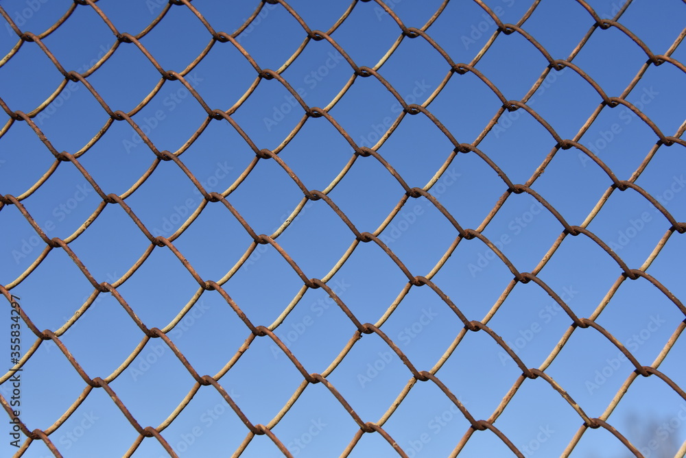 Metallic fence net against the sky Metallic fence net against the sky