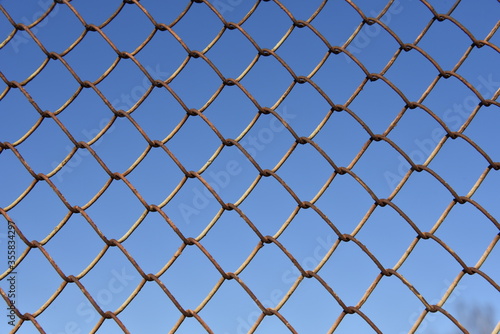 Metallic fence net against the sky