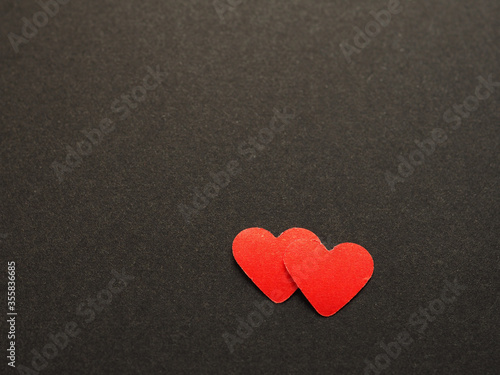 Two red paper heart shape on black background of your text. The concept for design, wallpaper, love. Top view. .