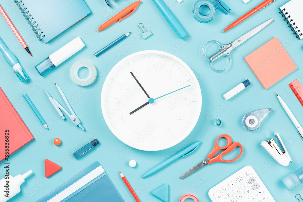 Assorted office and school white orange and blue stationery supply on pastel trendy background as knolling. White clock. Flat lay for back to school or education and craft concept. Assorted office and school white orange and blue stationery supply on pastel trendy background as knolling. White clock. Flat lay for back to school or education and craft concept.
