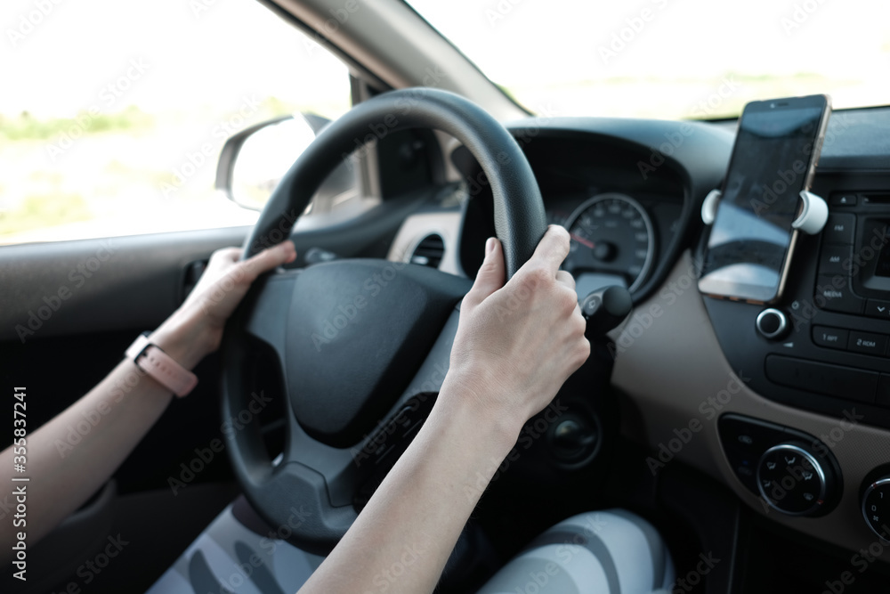 woman's hands holding steering wheel while driving a car