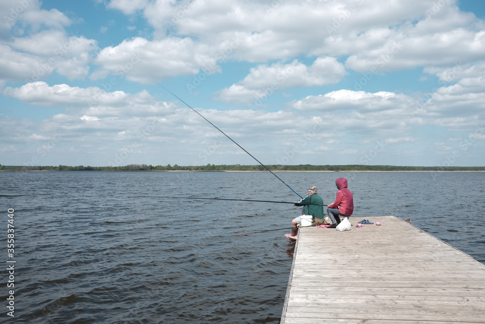 Senior couple fishing on the pier of lake Senior couple fishing on the pier of lake