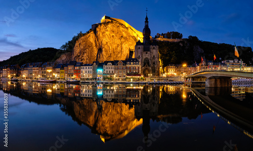 Night view of Dinant town, Collegiate Church of Notre Dame de Dinant over River Meuse and Pont Charles de Gaulle bridge and Dinant Citadel illuminated in the evening. Dinant, Belgium photo