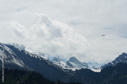 Alpine peaks lanscape in early spring with a paraglider flying above. Engelberg region in Obwalden canton Switzerland.