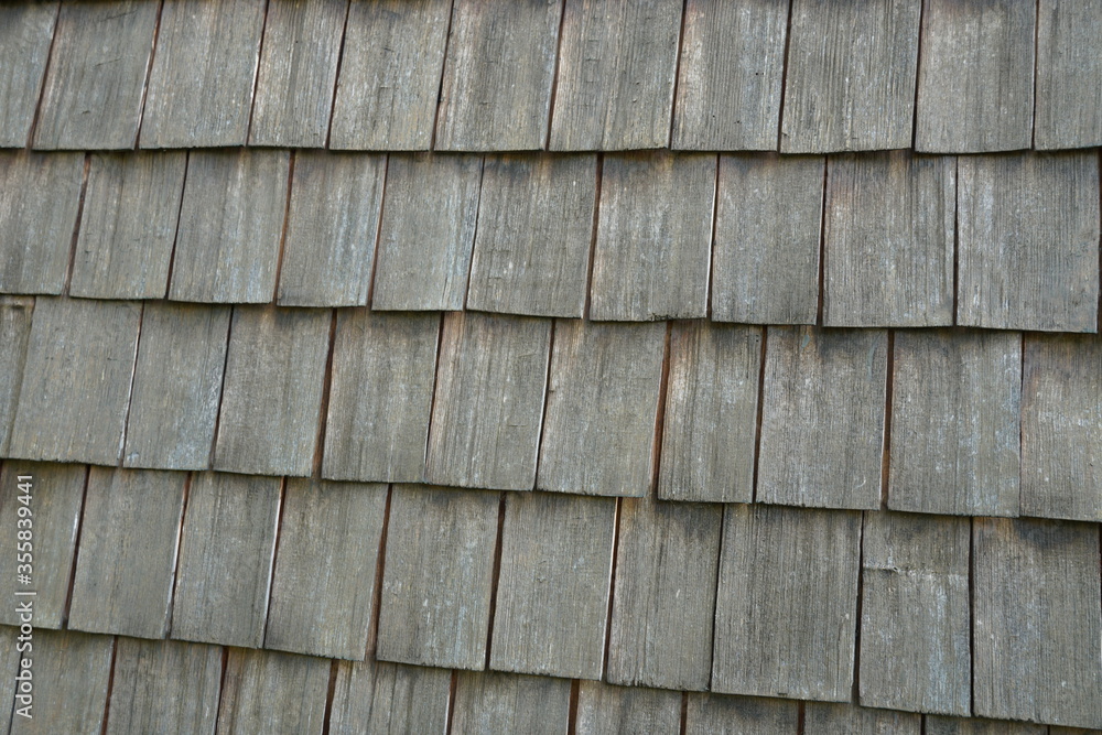 A wooden shingle in neat rows on a roof close up. A detail of a roof of a traditional Swiss countryside. A wooden shingle in neat rows on a roof close up. A detail of a roof of a traditional Swiss countryside.