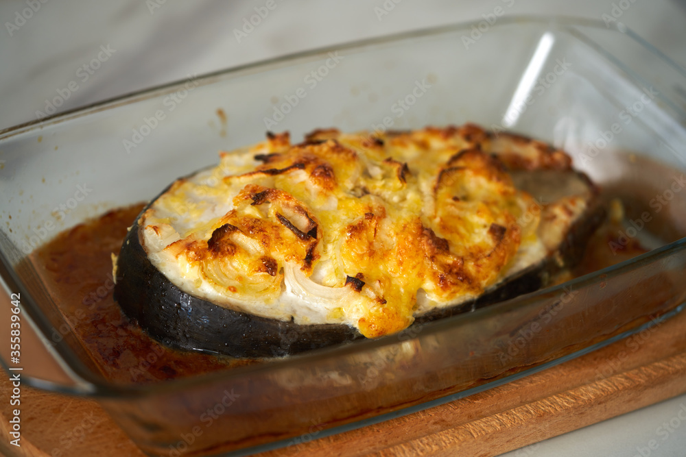 baked fish with cheese lies on a transparent dish baked fish with cheese lies on a transparent dish