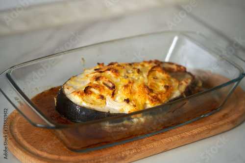 baked fish with cheese lies on a transparent dish