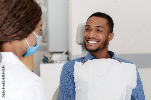 Young black man smiling to female dentist doctor