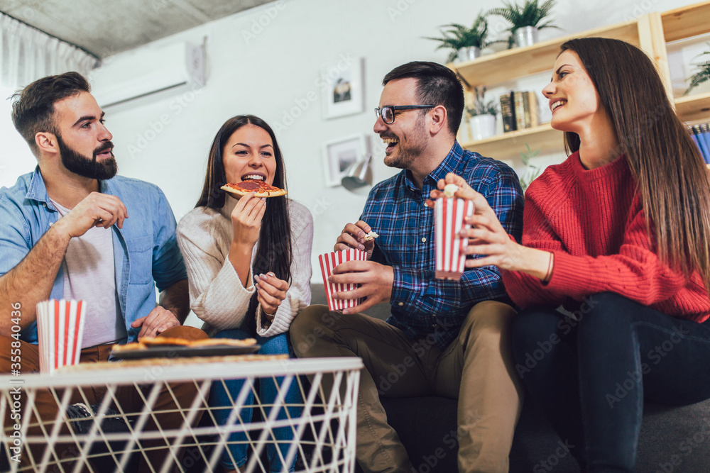 Group of young friends eating pizza in home interior. Young people having fun together. Group of young friends eating pizza in home interior. Young people having fun together.