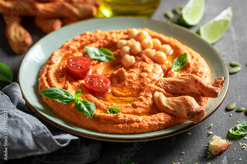 Traditional tomato hummus with breadsticks and basil