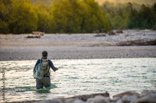 Close up of a fly fisherman casts his line while wading in the middle of a river