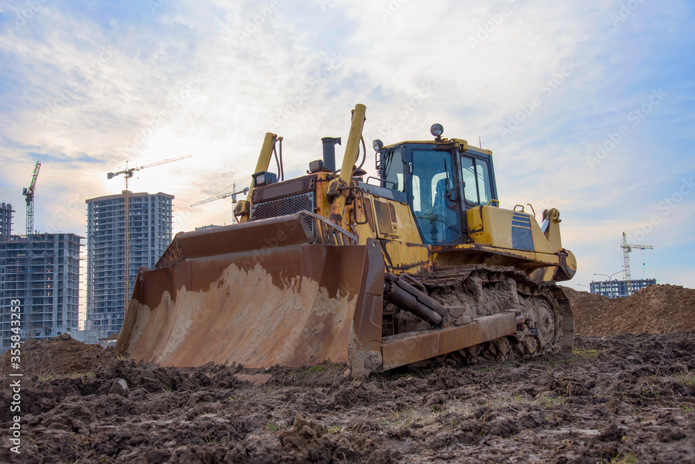 Dozer with bucket for pool excavation and utility trenching. Bulldozer during land clearing and foundation digging at construction site. Earth-moving equipment background