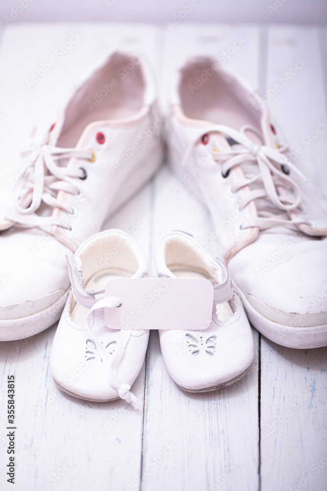 Two pairs of sports shoes on a white wooden background. The shoes of father and son or daughter. Fathers day concept.