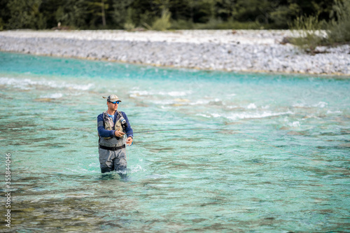 A fly fisherman casts his line while wading in the middle of a river