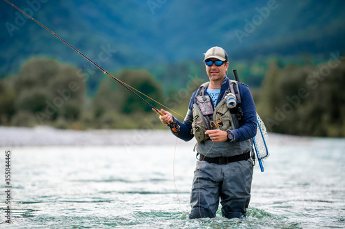 Close up of a fly fisherman casts his line while wading in the middle of a river