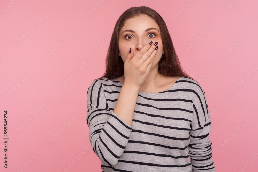 I won't say anyone. Portrait of scared intimidated woman in striped sweatshirt covering mouth and looking with frightened eyes, terrified to talk, keeping terrible secret. indoor studio shot isolated I won't say anyone. Portrait of scared intimidated woman in striped sweatshirt covering mouth and looking with frightened eyes, terrified to talk, keeping terrible secret. indoor studio shot isolated