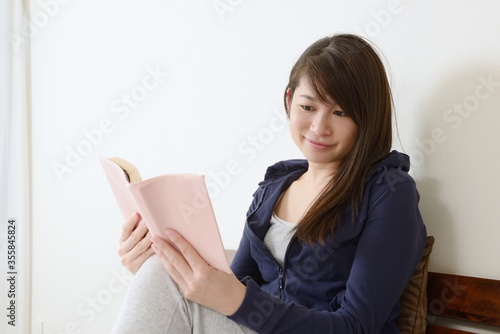 ベッドに座って本を読む女性