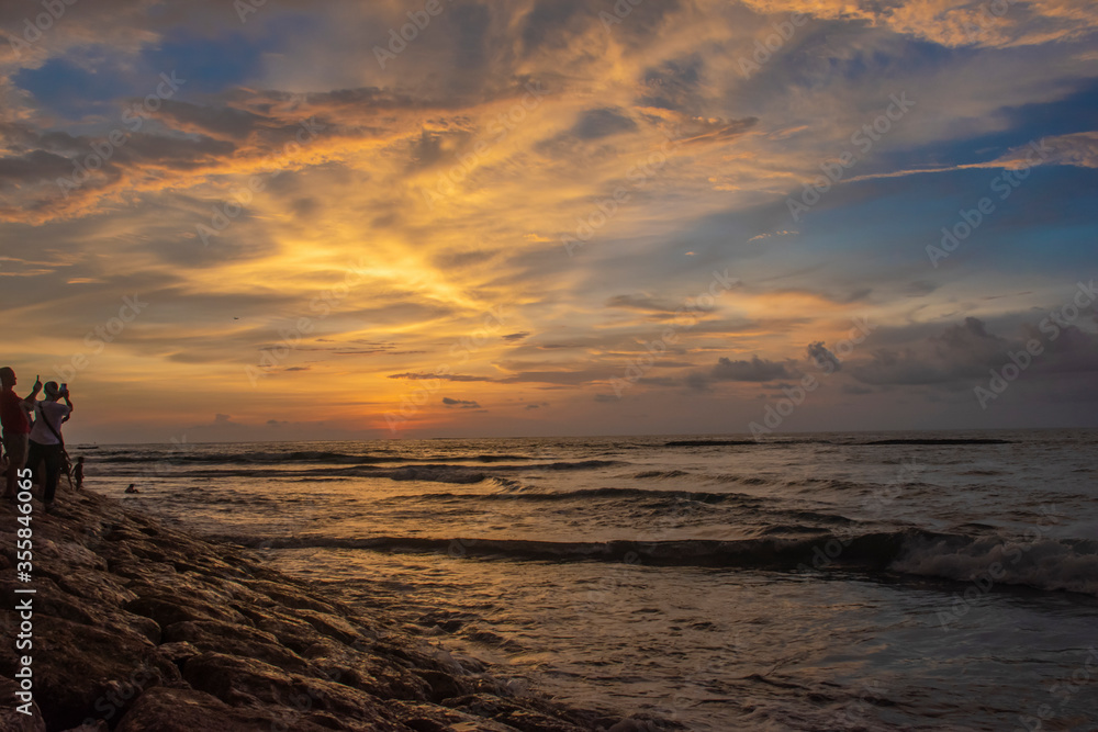 People are trying to take the picture of beautiful sunset through the horizon from the seashore in Bali