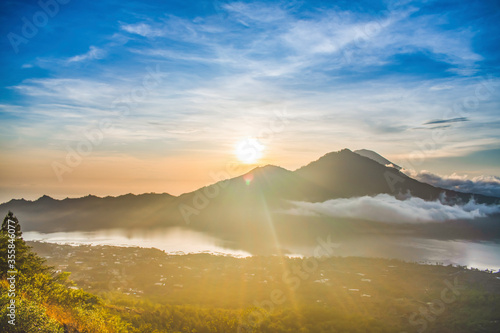A spectacular panoramic view of kintamani volcano peak, sunrise and sunrays from the top of the Mount Batur photo